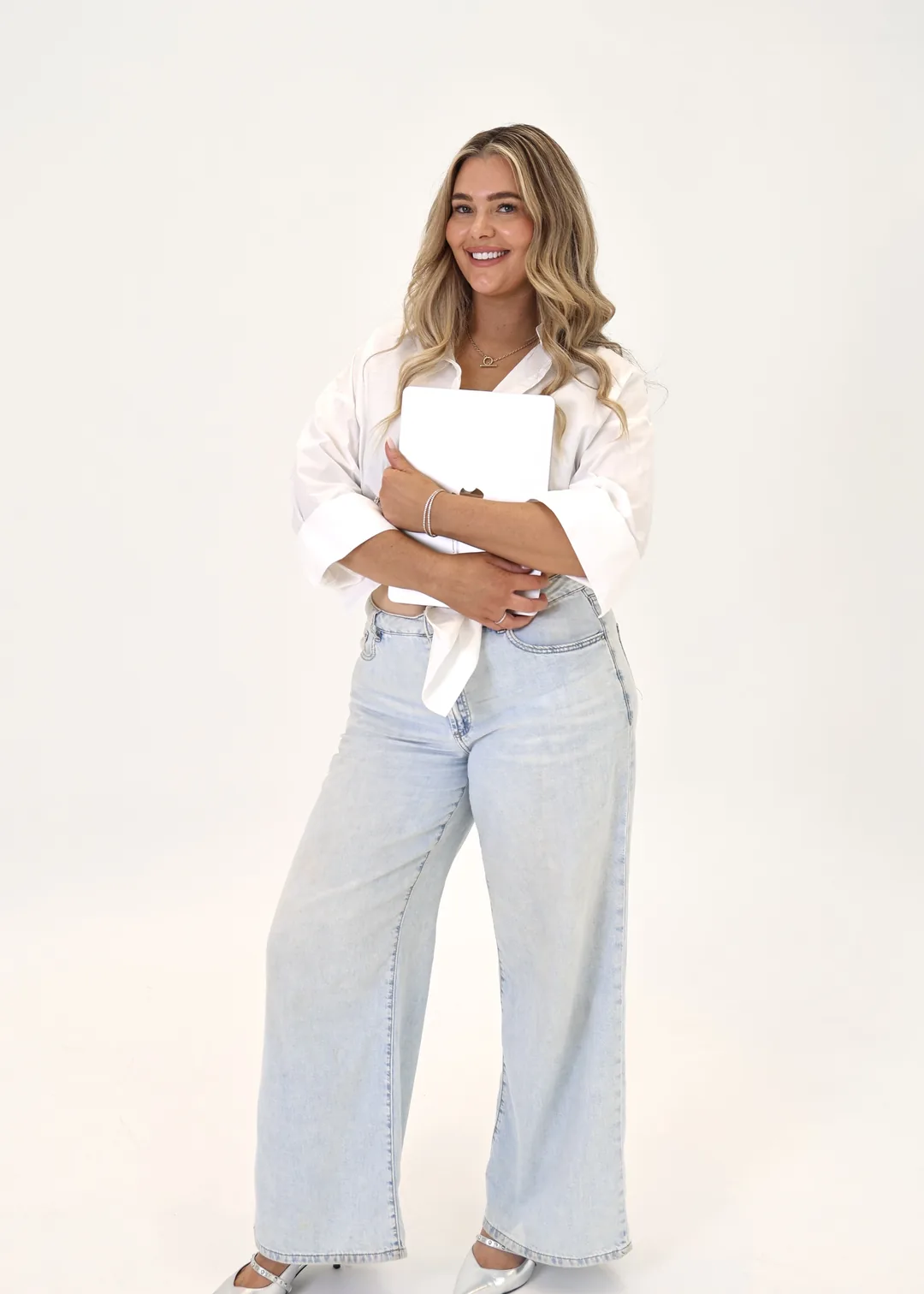 Krystle standing with a laptop in a white shirt